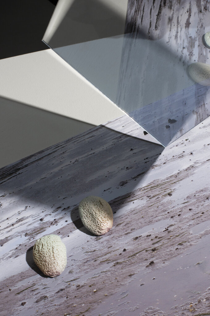 Print of beach scape with mirror on top giving a reflection. A pair of earrings sit on top