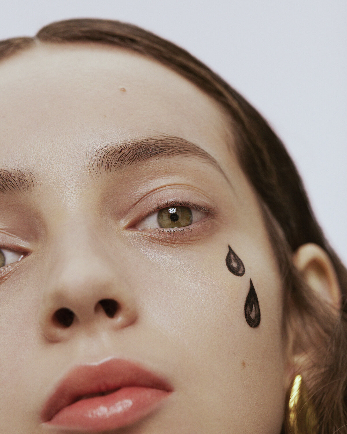 Close portrait of a woman who has exaggerated tear drops drawn on her face