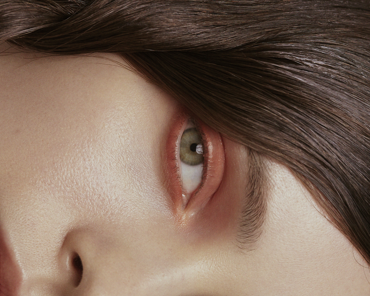 A side view of a woman's eye with pinky-red eye shadow
