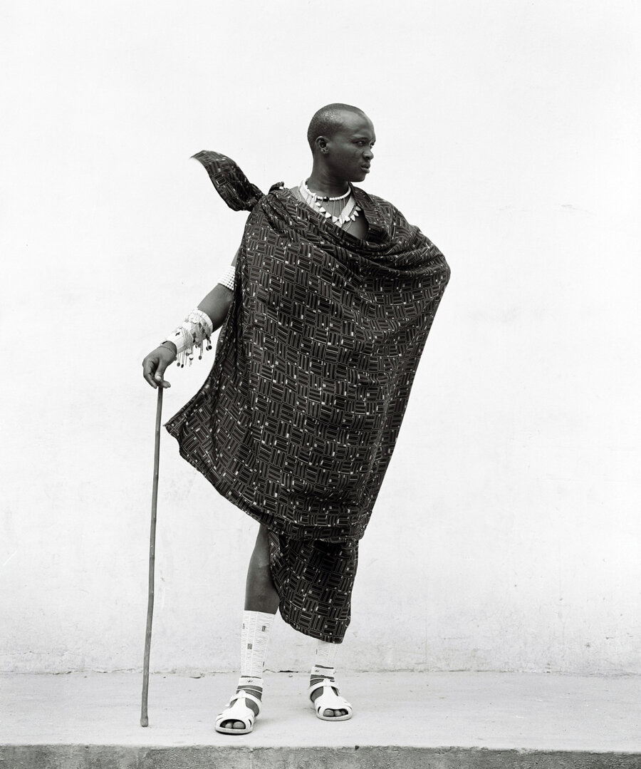 A Massai man standing in front of a white coloured wall.