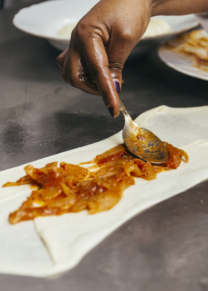 Crepe being filled with onion mixture