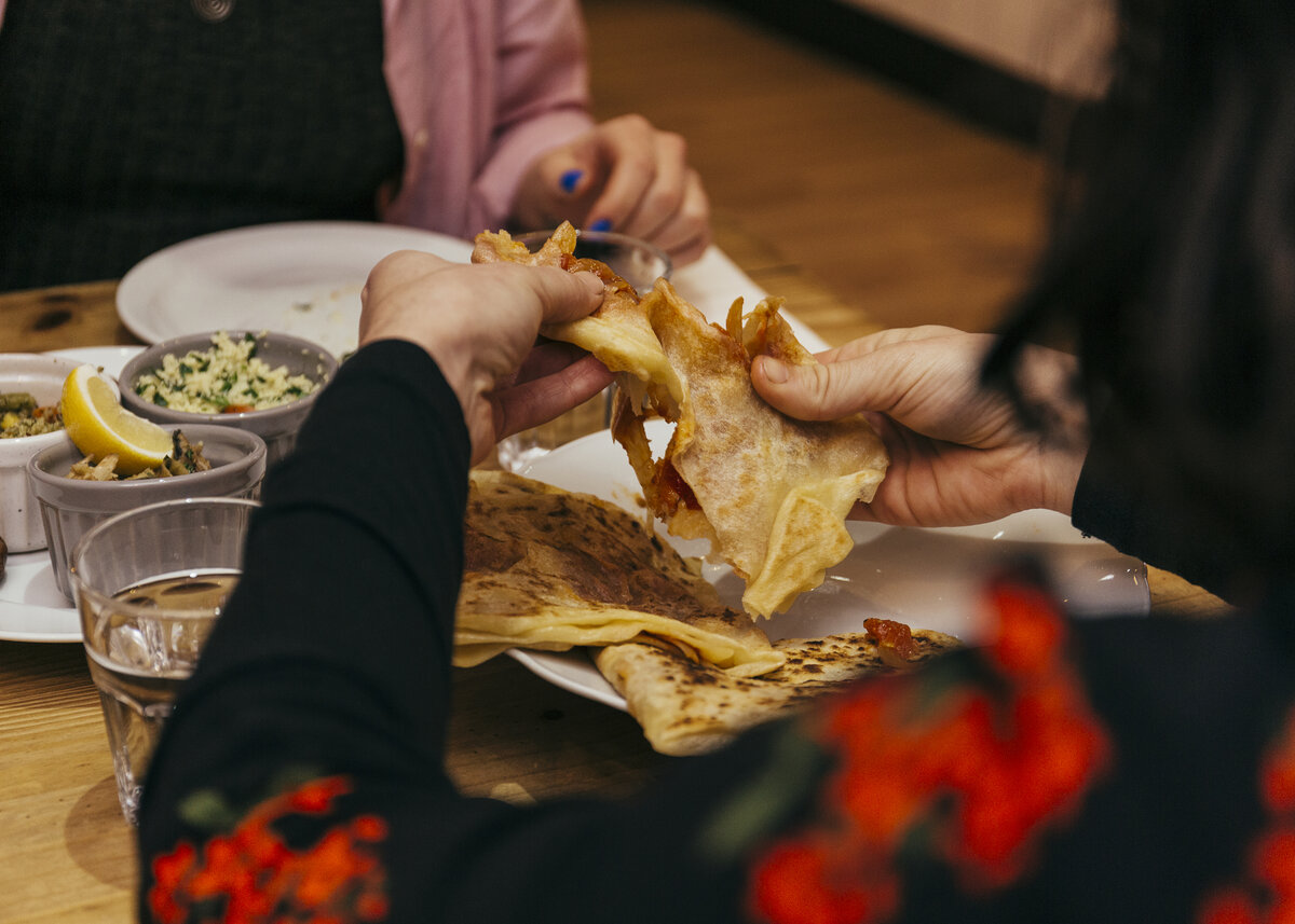 Over the shoulder view of a woman breaking bread